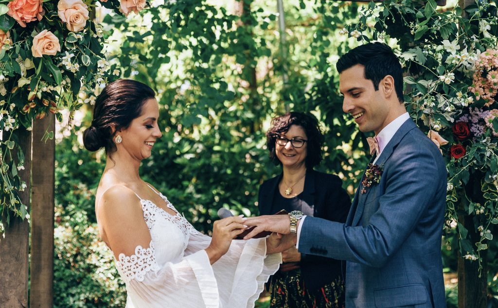 Couple exchanging rings with their celebrant at a garden wedding