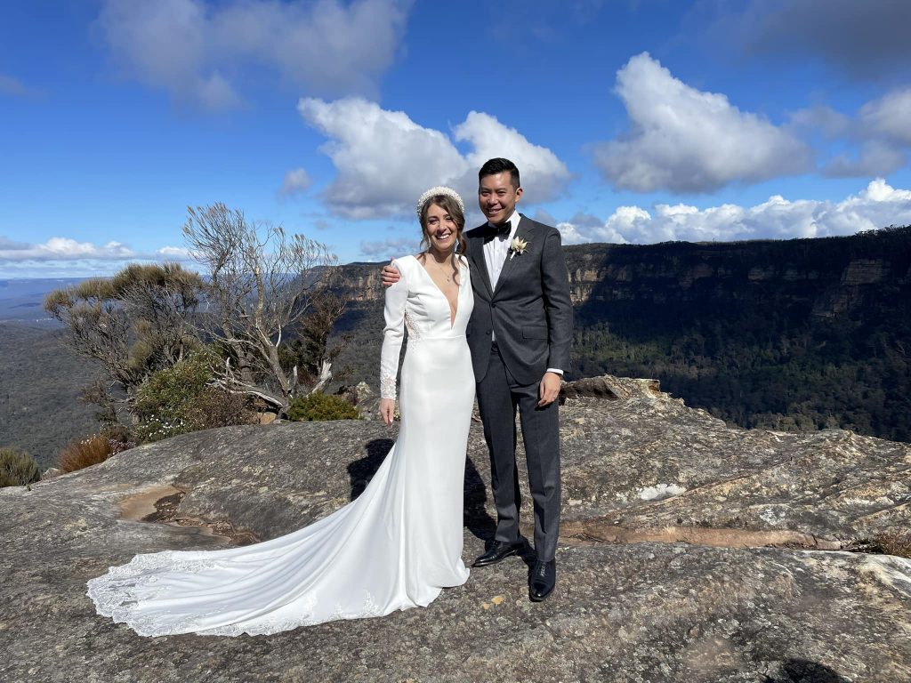 Bride and groom on a sandstone lookout above the Blue Mountains valleys